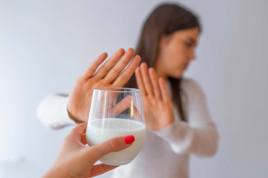 Intolerância à Lactose (IL) Imagem de Mulher rejeitando com copo de leite devido à intolerância à lactose