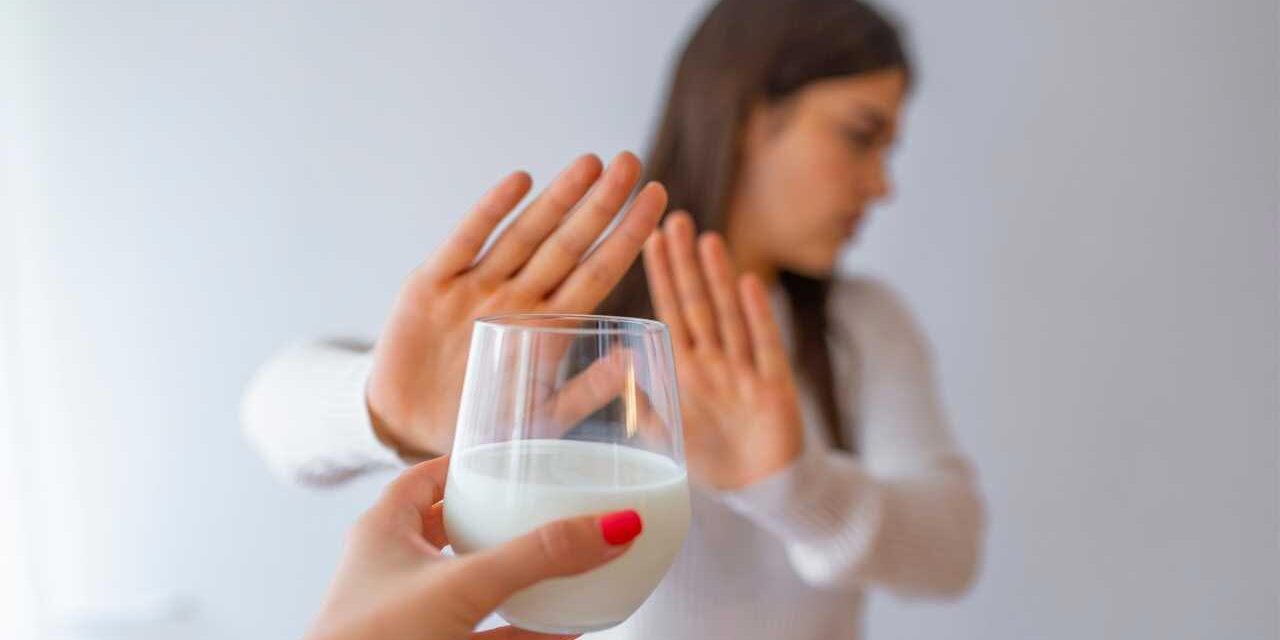 Intolerância à Lactose (IL) Imagem de Mulher rejeitando com copo de leite devido à intolerância à lactose